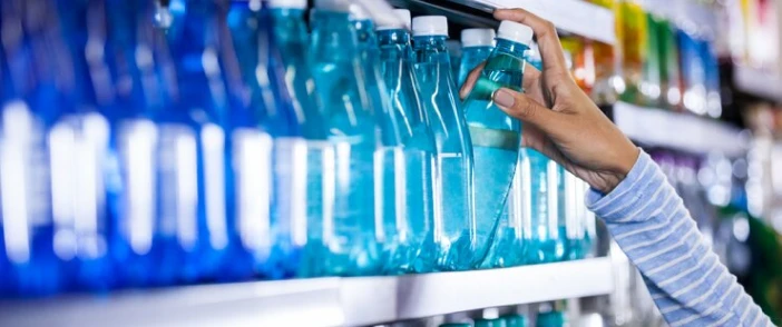 A shopper picking a bottled beverage from a store shelf