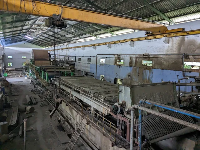 The interior of a paper mill with a paper machine and overhead crane, inspected for valuation