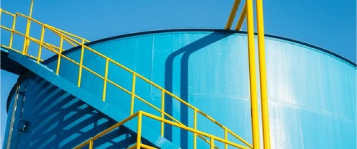 A petrochemical storage tank with yellow access stairways