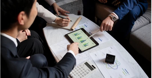 A team reviewing valuation charts on a tablet around a table